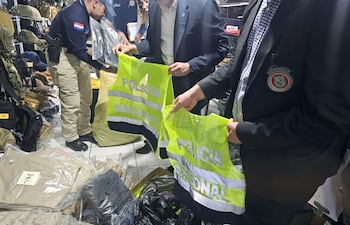 Agentes del Departamento Especializado contra la Violación de Derechos Intelectuales muestran los chalecos policiales que fueron incautados.