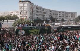 (ARCHIVOS) Aficionados vitorean mientras los futbolistas senegaleses desfilan en autobús por las calles de Dakar el 20 de enero de 2026, celebrando la victoria de Senegal en la Copa Africana de Naciones (CAN), celebrada en Marruecos. Los hinchas senegaleses criticaron duramente la decisión de la AFCON de despojar a Senegal de su título y otorgárselo a Marruecos, calificando la medida de "una vergüenza para África" al enterarse de la noticia el miércoles.