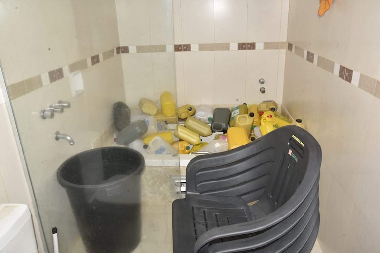 Ambiente desordenado con botellas y balde en cuarto, sin personas visibles.