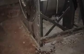 Equipo industrial metálico en lavandería del Hospital Psiquiátrico, rodeado de suciedad en un ambiente cerrado y descuidado.