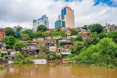 Vista de un paisaje urbano con edificios altos y casas precarias en la inundada San Rafael, rodeadas de vegetación.
