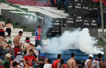 Los efectivos de la Policía Nacional lanzando los gases lacrimógenos a los integrantes de la barra brava de Cerro Porteño, en el enfrentamiento en el sector de Graderías Norte del estadio Defensores del Chaco.