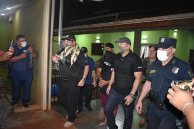 Los fiscales Federico Delfino y Lorenzo Lezcano (con chalecos negros), salen con el detenido Alcides Villasboa de la casa allanada ayer en Pedro Juan Caballero.