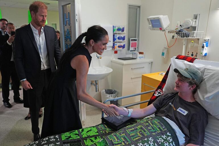 El príncipe Harry y su esposa Meghan junto a un paciente durante una visita a la sala de oncología y rehabilitación para adolescentes del Royal Children's Hospital en Melbourne. (Jonathan Brady / POOL / AFP)