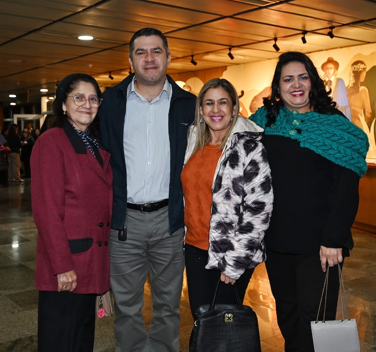 Carolina De Bestard sonríe junto a tres personas, en un ambiente festivo con decoraciones de fondo.