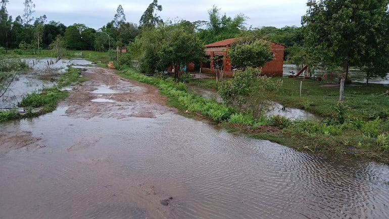 Paisaje rural inundado en Santa Rita Taturuguá, con un camino de tierra sumergido y vegetación a los lados.