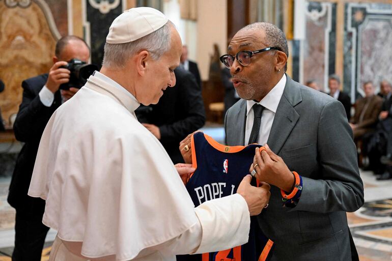 León XIV recibiendo una camiseta de los New York Knicks de manos del director Spike Lee.  (Handout / VATICAN MEDIA / AFP)