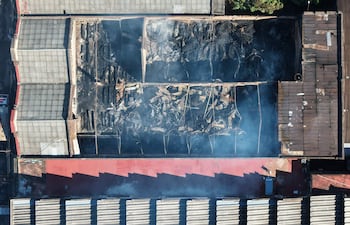 Vista aérea de un depósito de Cañas Paraguayas SA, parcialmente destruido, con humo y escombros visibles.