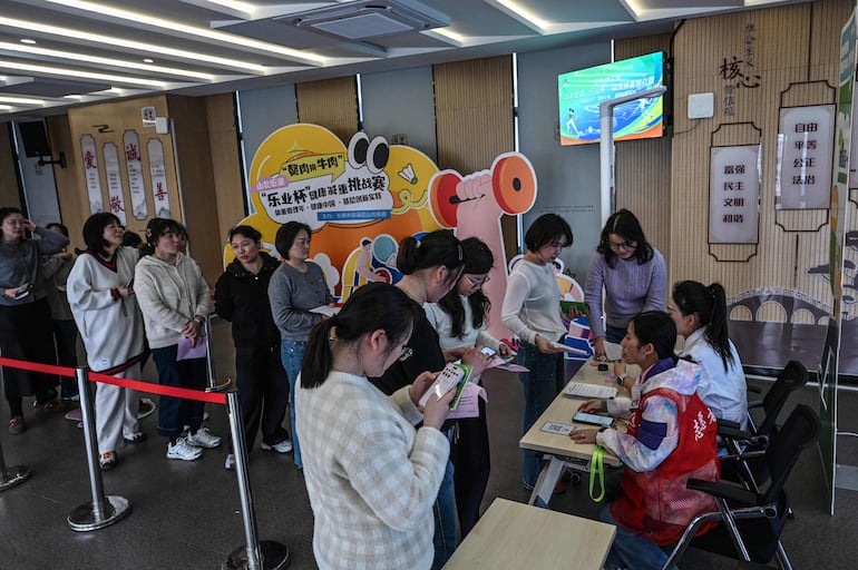 La fotografía tomada el 23 de marzo de 2026 muestra a mujeres haciendo fila para pesarse en un centro comunitario local en Wuxi, en la provincia de Jiangsu, en el este de China.