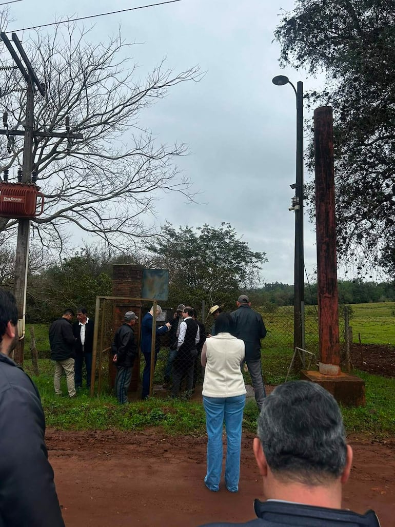 Grupo de personas en conversación, entre ellas abogados, en ambiente al aire libre con árboles y cielo nublado.