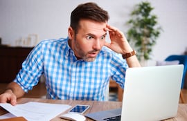 Un hombre de mediana edad con una expresión de preocupación mira la computadora.