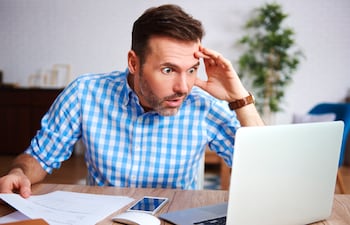 Un hombre de mediana edad con una expresión de preocupación mira la computadora.