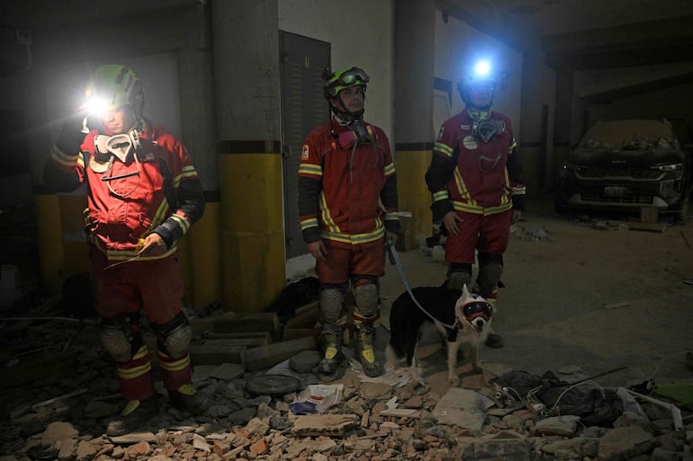 Rescatistas mexicanos y Halley, el perro que ayudó a localizar a Hernán Gil, ingresan al garaje del edificio desde el que fue rescatado en Catia La Mar, estado de La Guaira, Venezuela, el 2 de julio de 2026, ocho días después de los terremotos gemelos.