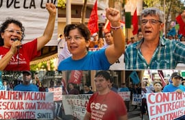 Mujer al micrófono con cabello rizado y camiseta roja, rodeada de personas levantando brazos en apoyo y sosteniendo carteles de educación.