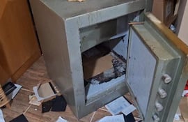 Caja fuerte de metal parcialmente abierta en un entorno desordenado de un motel tras un asalto violento.