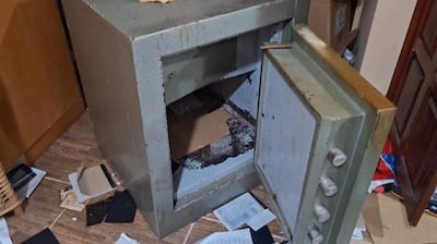Caja fuerte de metal parcialmente abierta en un entorno desordenado de un motel tras un asalto violento.
