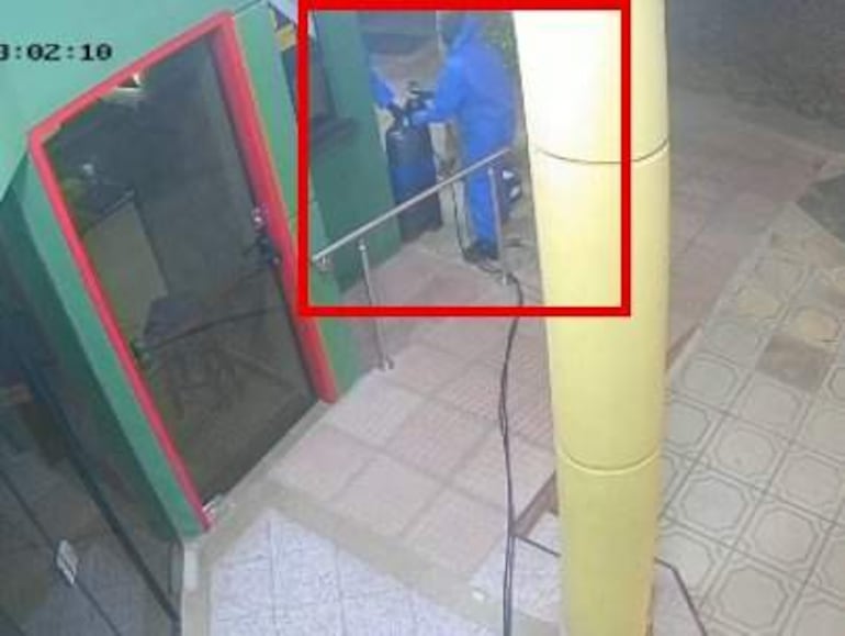 Persona con overol azul de espaldas junto a balones de oxígeno en la entrada de un negocio.