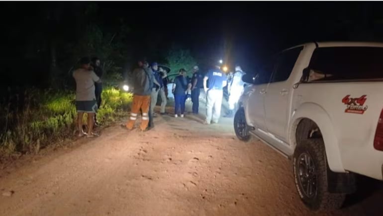 Vecinos y policías rodean el automóvil Toyota Vitz que abandonaron los presuntos asaltantes en Villa Hayes.