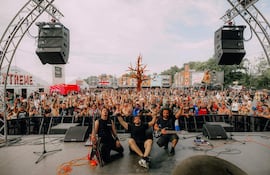 Músicos en el escenario del Hellfest, con la multitud animando y levantando las manos en señal de alegría.