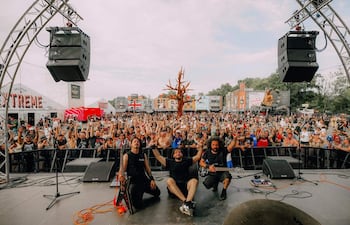Músicos en el escenario del Hellfest, con la multitud animando y levantando las manos en señal de alegría.