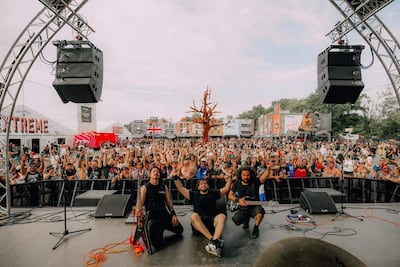 Músicos en el escenario del Hellfest, con la multitud animando y levantando las manos en señal de alegría.
