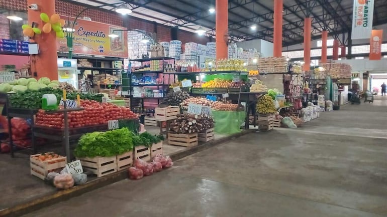 Puestos de frutas y verduras en Mercado de Abasto, con etiquetas de precios visibles y ambiente comercial activo.