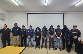 Grupo de seis personas, tres con gorras de la PFA, discuten en ambiente formal con un proyector apagado al fondo.