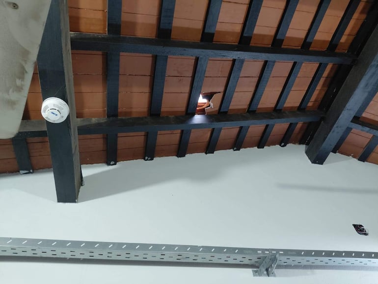 Techo de la Escuela Juan Alberto Samaniego con vigas de madera expuestas y un agujero por el que entra luz.
