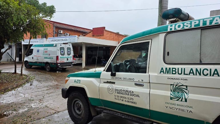 Ambiente hospitalario con ambulancias SEME 141 y A-270, letreros de urgencias pediátricas y cirugía en un día lluvioso.