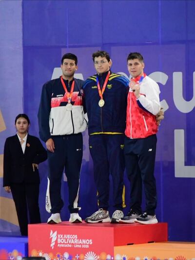 Charles Hockin (d) ganó  bronce en  100 m  mariposa. Plata para Vargas (CHI) y oro para Rincón (COL).