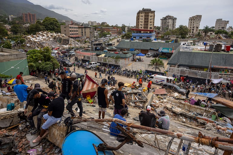 Personas observan edificios colapsados por los terremotos, en La Guaira (Venezuela).