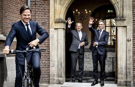 El nuevo primer ministro de Países Bajos Dick Schoof (derecha) y el secretario general del Ministerio de Asuntos Generales Gert-Jan Buitendijk (C) saludan al exprimer ministro Mark Rutte cuando este se retira del Torentje, como se llama la oficina del primer ministro.