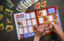 Un joven coleccionista pega una figurita de la selección nacional de fútbol de Suiza en el álbum oficial Panini de la Copa Mundial de la FIFA 2026, en Lausana, Suiza, el 12 de mayo de 2026.