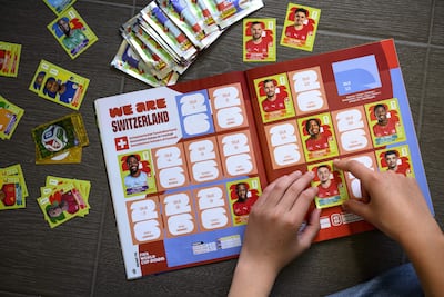 Un joven coleccionista pega una figurita de la selección nacional de fútbol de Suiza en el álbum oficial Panini de la Copa Mundial de la FIFA 2026, en Lausana, Suiza, el 12 de mayo de 2026.