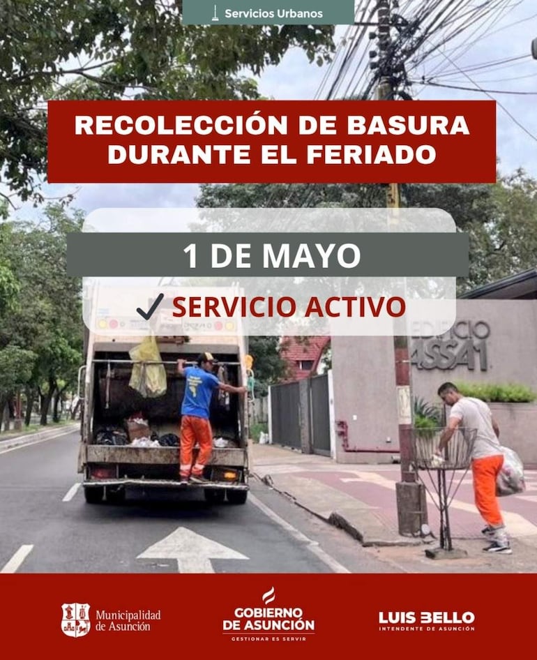 Dos trabajadores en camisetas azules y pantalones naranjas recogen basura junto a un camión en una calle con árboles.