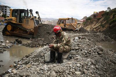 Un militar descansa al lado de maquinaria usada para remover escombros, cerca de casas colapsadas por la crecida de ríos en la zona Callapa, Bolivia, el pasado viernes.