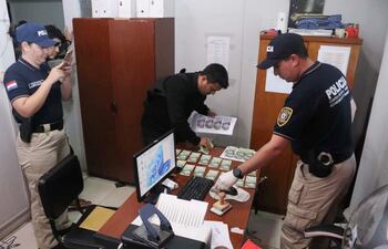 Investigadores de la Policía Nacional y el Ministerio Público analizan los billetes utilizados durante la entrega vigilada durante la intervención en la Fiscalía Zonal de Emboscada.