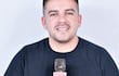 César Candia con micrófono en mano, sonriente, con micrófono del SNT en un ambiente informal.