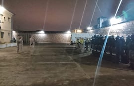Grupo de policías con uniformes oscuros, alineados y sosteniendo escudos en el proceso de traslado de mujeres privadas de su libertad.