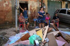 Una familia conversa en la calle frente a una pila de escombros en Heliopolis, en Belford Roxo, Río de Janeiro.