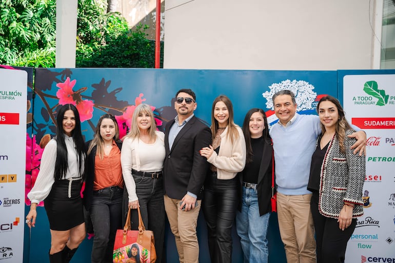 Nora Rodríguez Norita y Bibi Landó sonríen en el evento, rodeadas de personas en vestimenta variada en un ambiente alegre.