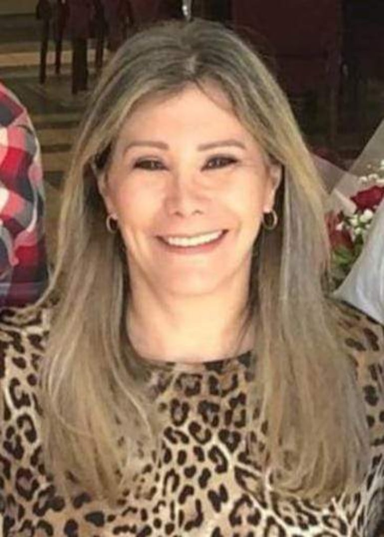 Mujer rubia sonriente con pendientes, iluminada por luces suaves en un ambiente festivo.