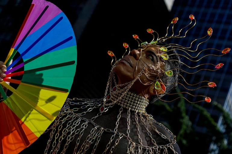 Espléndidamente adornado y con un abanico con los colores del arcoiris, uno de los participantes de la marcha del orgullo en Brasil