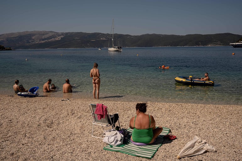 Turistas descansan en una playa de la isla de Ítaca, en el mar Jónico, el 3 de agosto de 2026.