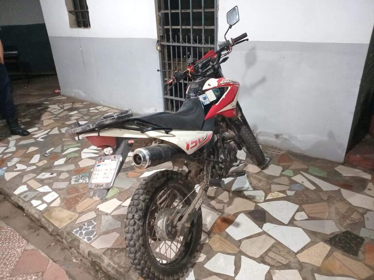 Motocicleta de uso recreativo en garaje con piso de baldosas, sin personas presentes.