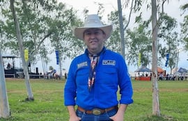 Lider Amarilla, sonriente, con camisa azul y sombrero blanco, vestido de jinete en un evento rodeado de árboles y césped.