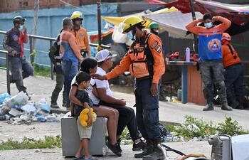 Un rescatista conversa con una pareja y un niño en Punta Tanaguarenas, Venezuela.