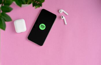 Un teléfono celular conectado a Spotify con dos auriculares