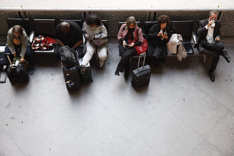 Pasajeros con equipaje esperan en la estación de Atocha (Madrid) este miércoles. 
