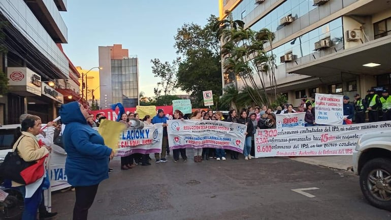 Enfermeras y trabajadores de salud en protesta, sosteniendo pancartas con mensajes de reclamo, en un ambiente urbano.